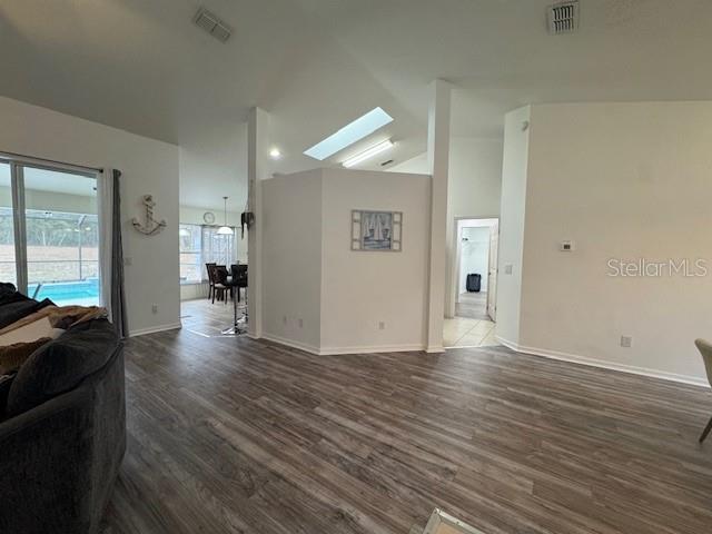 living room with vaulted ceiling with skylight and dark hardwood / wood-style floors