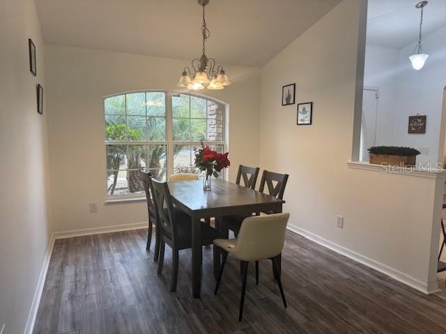 dining space featuring vaulted ceiling, dark wood-type flooring, and an inviting chandelier