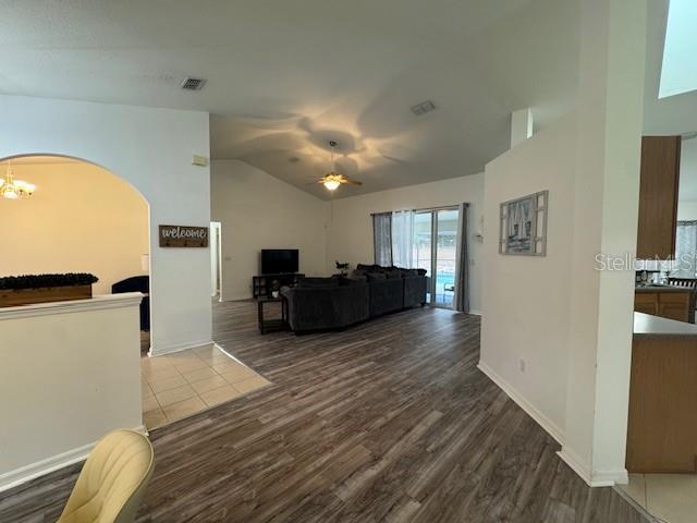 living room with ceiling fan with notable chandelier and hardwood / wood-style floors