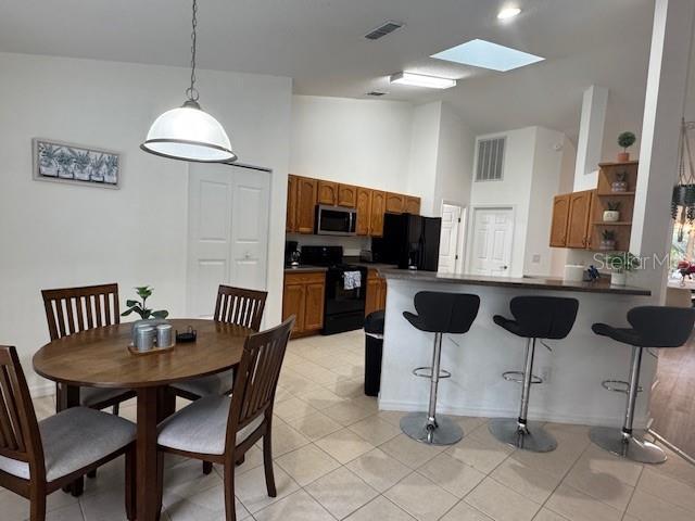 kitchen with decorative light fixtures, black appliances, kitchen peninsula, and a breakfast bar area