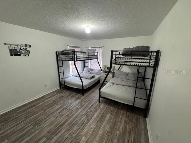 bedroom featuring a textured ceiling and dark hardwood / wood-style flooring