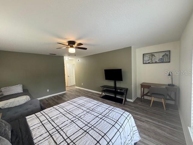 bedroom with dark wood-type flooring, ceiling fan, and a textured ceiling