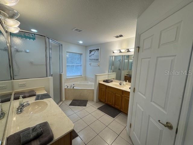 bathroom with separate shower and tub, vanity, tile patterned floors, and a textured ceiling