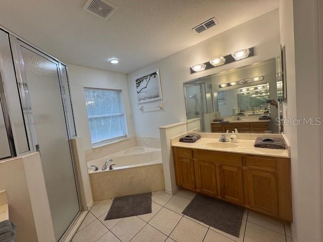 bathroom featuring a textured ceiling, shower with separate bathtub, tile patterned floors, and vanity