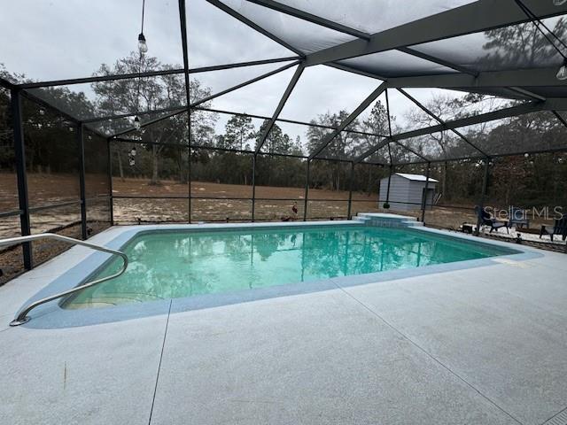 view of pool with a patio area, a lanai, and a storage unit