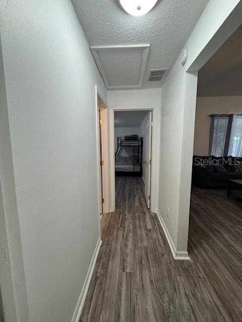 hall with a textured ceiling and dark hardwood / wood-style flooring