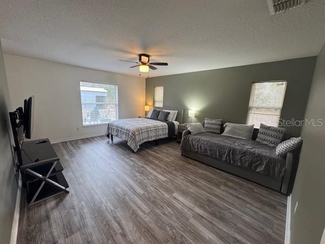 bedroom with ceiling fan, dark wood-type flooring, and a textured ceiling