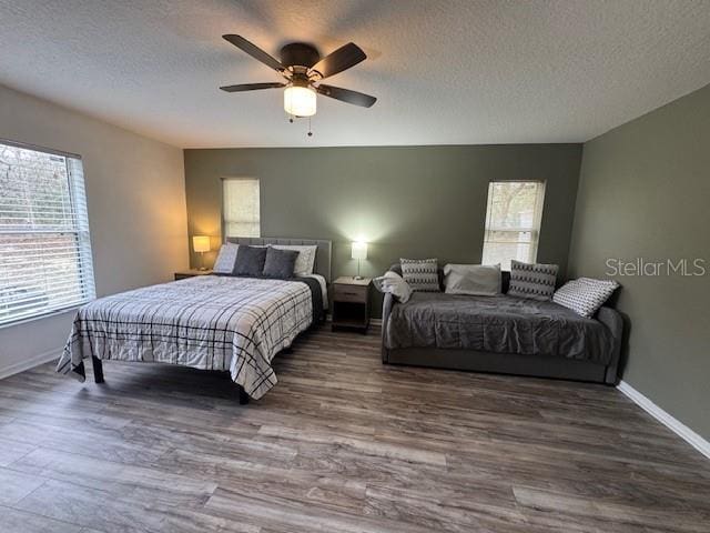 bedroom with a textured ceiling, ceiling fan, and dark hardwood / wood-style floors