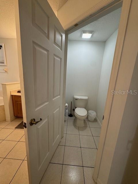 bathroom with toilet, tile patterned floors, and a textured ceiling