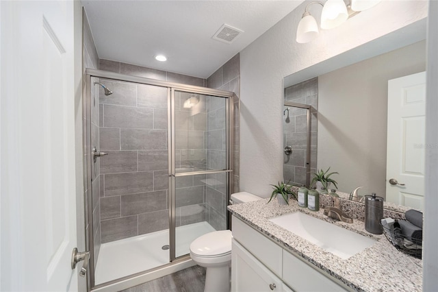 bathroom with vanity, hardwood / wood-style flooring, toilet, and a shower with shower door