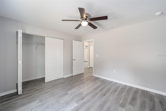 unfurnished bedroom featuring a closet, light hardwood / wood-style flooring, and ceiling fan