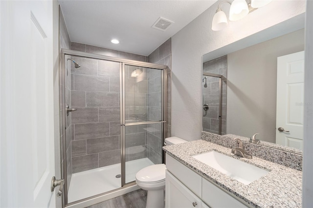 bathroom with hardwood / wood-style floors, vanity, toilet, and a shower with door