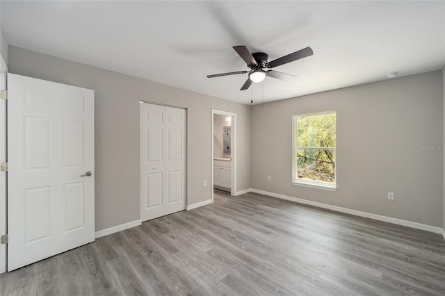 unfurnished bedroom with ceiling fan, light wood-type flooring, and ensuite bathroom