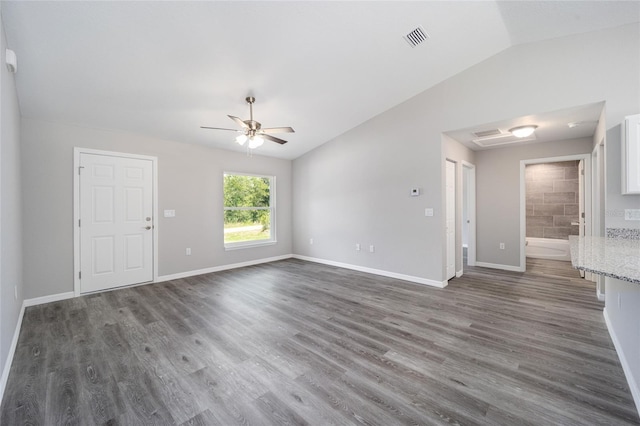 unfurnished living room featuring dark hardwood / wood-style flooring, vaulted ceiling, and ceiling fan