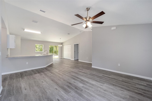 unfurnished living room with ceiling fan, sink, dark wood-type flooring, and vaulted ceiling