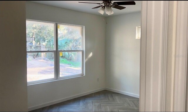 spare room featuring light parquet flooring, a wealth of natural light, and ceiling fan