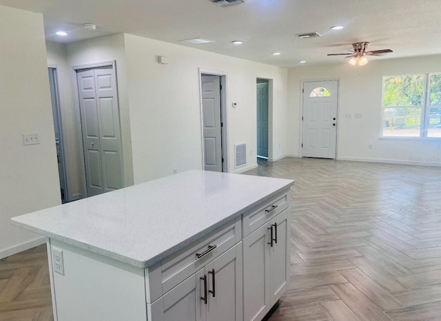kitchen with recessed lighting, a kitchen island, baseboards, visible vents, and a ceiling fan