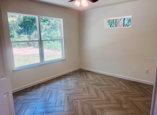 empty room with a ceiling fan, a wealth of natural light, and baseboards