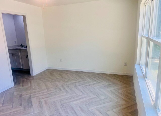 unfurnished room with baseboards and a sink