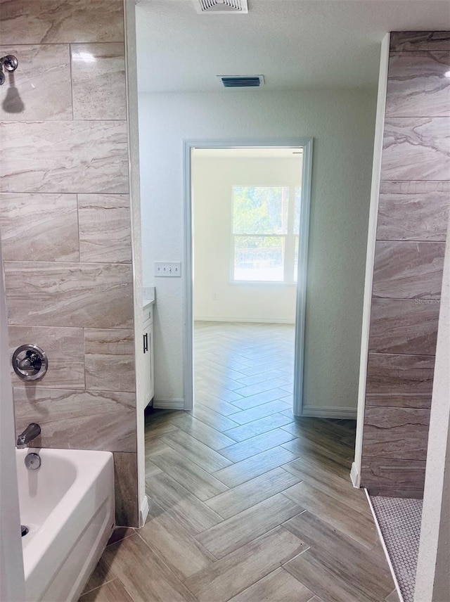 bathroom with visible vents, tub / shower combination, and baseboards