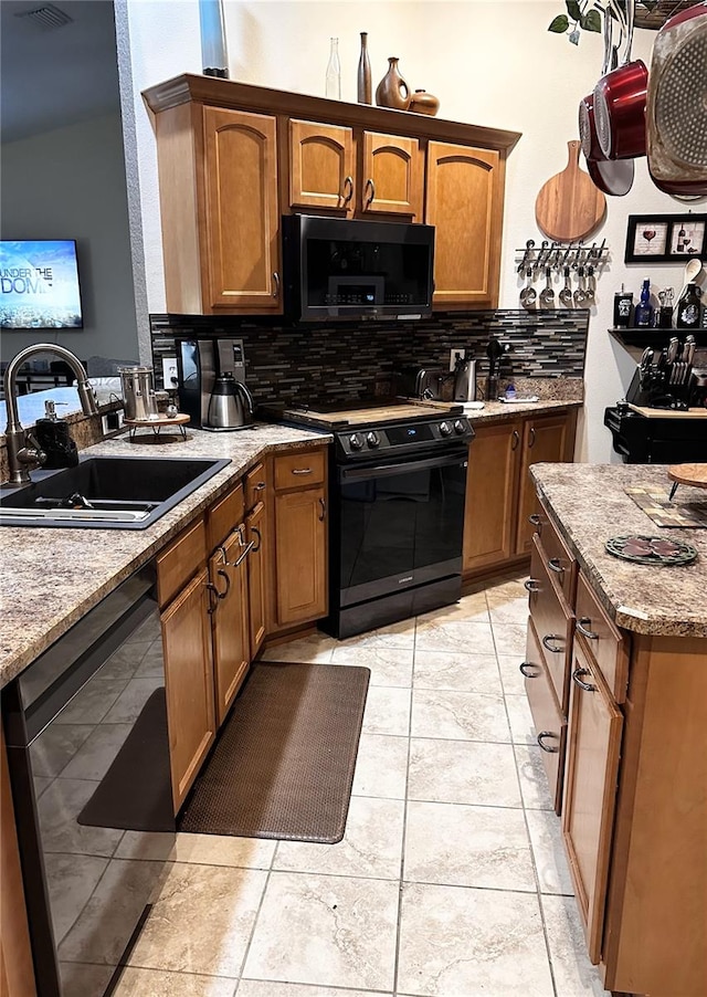 kitchen featuring black appliances, backsplash, light tile patterned floors, and sink