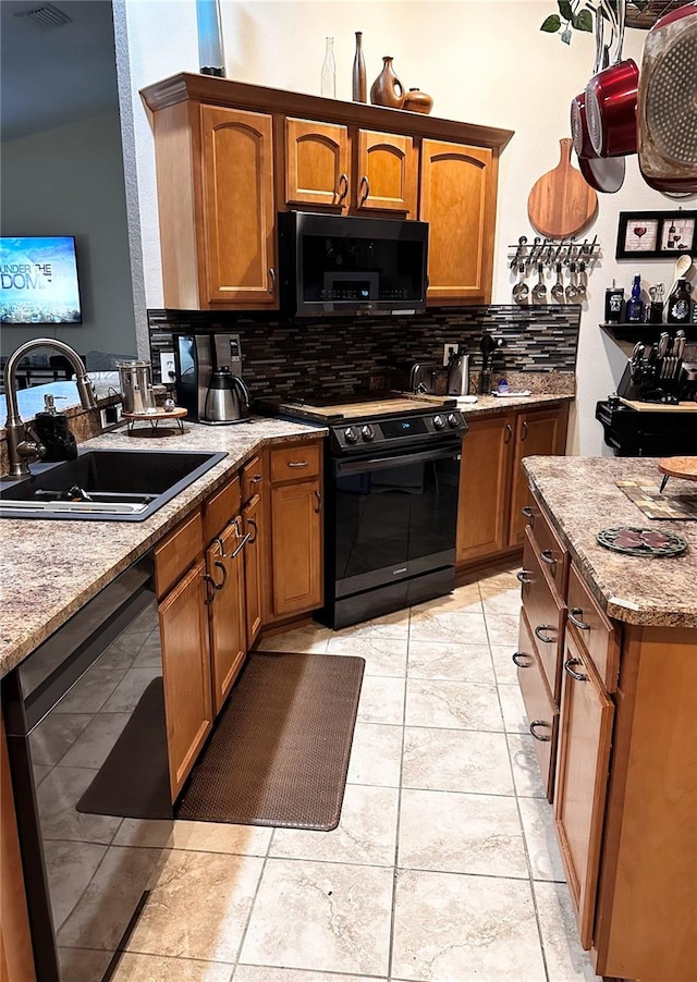 kitchen featuring black appliances, light stone countertops, tasteful backsplash, light tile patterned floors, and sink