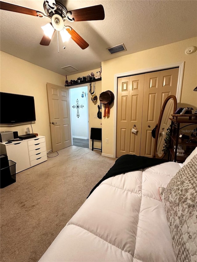 bedroom with a textured ceiling, light colored carpet, a closet, and ceiling fan