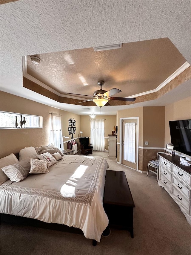 carpeted bedroom with crown molding, a textured ceiling, ceiling fan, and a raised ceiling