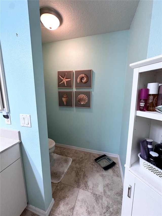 bathroom featuring toilet, a textured ceiling, and vanity