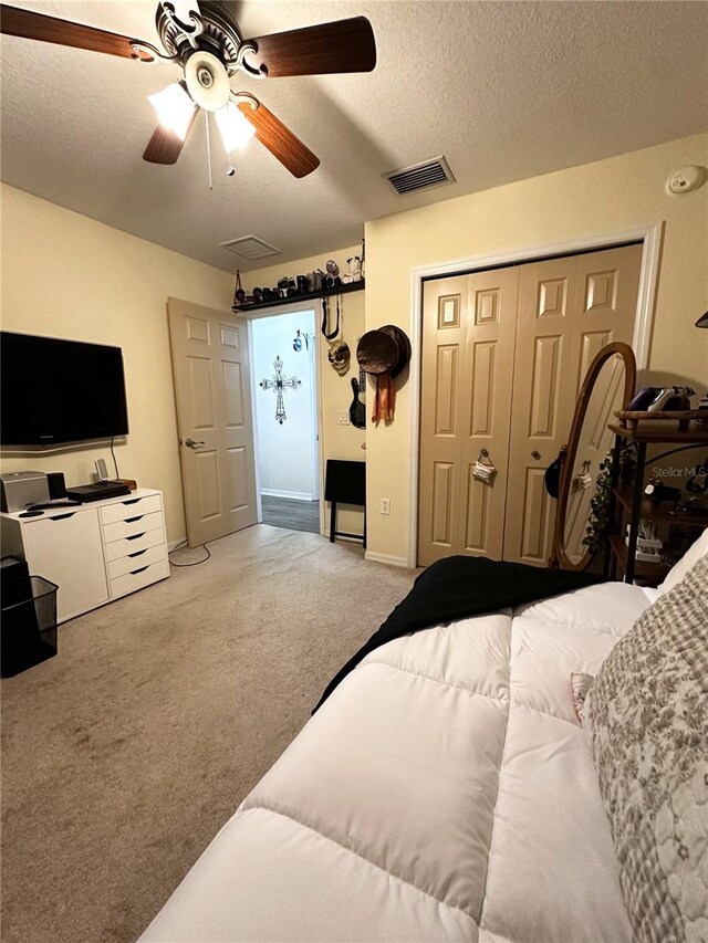 carpeted bedroom with ceiling fan, a textured ceiling, and a closet