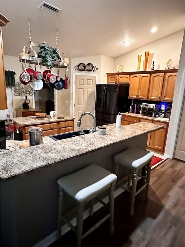 kitchen with a kitchen bar, black refrigerator, sink, dark hardwood / wood-style floors, and kitchen peninsula