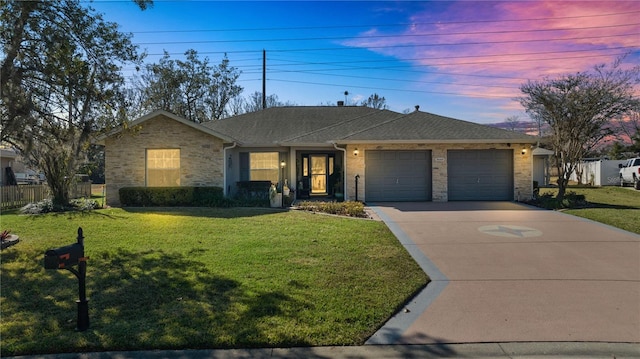 ranch-style home with a garage and a lawn