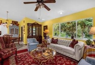 living room featuring ceiling fan with notable chandelier