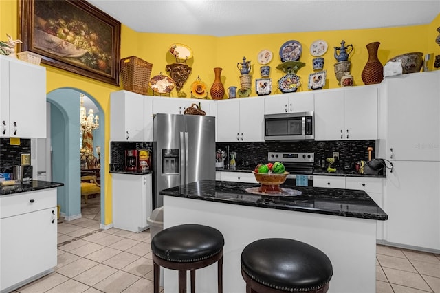 kitchen featuring tasteful backsplash, a kitchen island, white cabinets, and appliances with stainless steel finishes