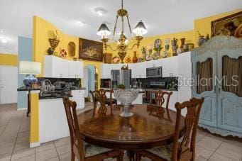 dining area with light tile patterned floors and an inviting chandelier