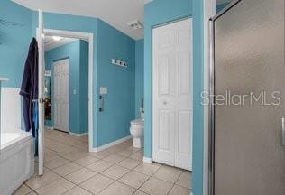 bathroom featuring toilet, tile patterned floors, and a shower with shower door