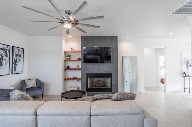 living room featuring a tile fireplace, crown molding, ceiling fan, and light tile patterned floors