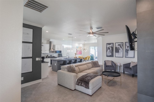 living room featuring ceiling fan with notable chandelier, crown molding, and sink