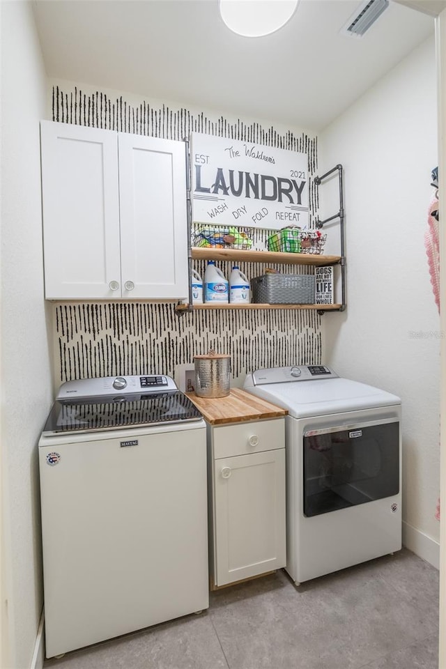 laundry room with washing machine and dryer and cabinets