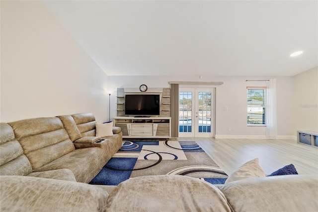 living room featuring light hardwood / wood-style floors, french doors, and lofted ceiling