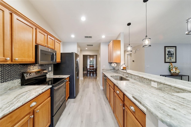 kitchen featuring pendant lighting, tasteful backsplash, light wood-type flooring, appliances with stainless steel finishes, and sink