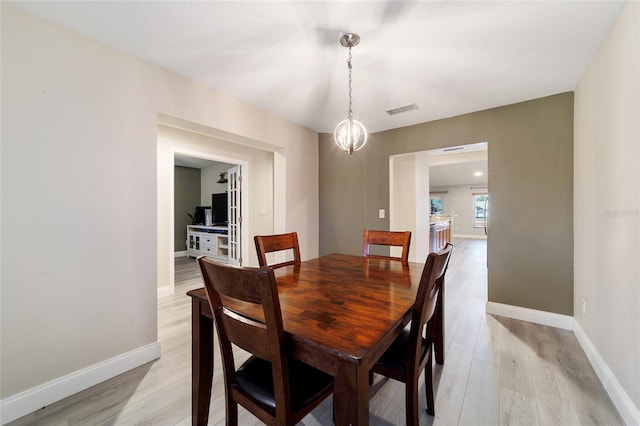 dining space featuring light hardwood / wood-style floors and a chandelier