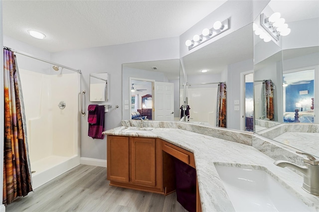 bathroom with a textured ceiling, ceiling fan, walk in shower, and vanity