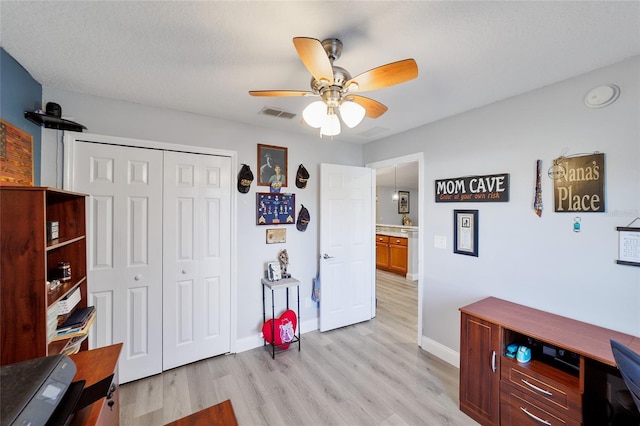 office featuring ceiling fan, light wood-type flooring, and a textured ceiling