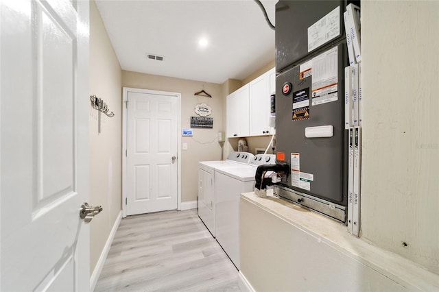 clothes washing area featuring light hardwood / wood-style floors, cabinets, and washer and clothes dryer