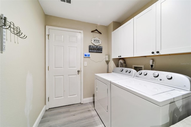 laundry room with separate washer and dryer, cabinets, and light hardwood / wood-style floors