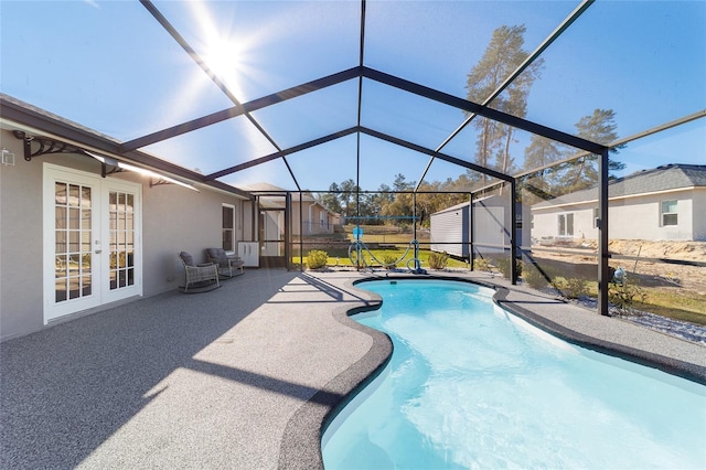 view of pool with a lanai, a patio, french doors, and a storage shed