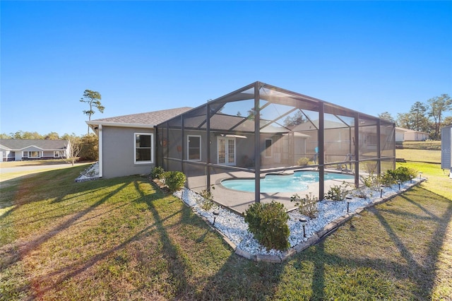 view of pool with a patio, glass enclosure, and a yard