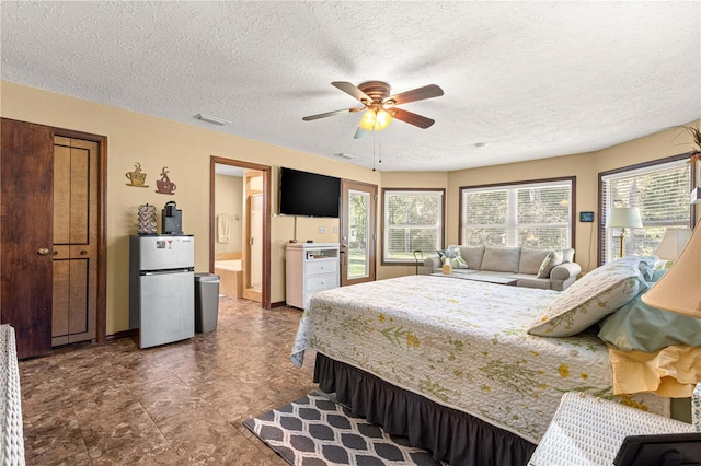 bedroom featuring ensuite bath, a textured ceiling, stainless steel refrigerator, and ceiling fan