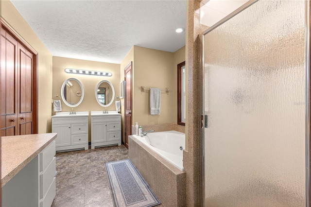 bathroom featuring a textured ceiling, plus walk in shower, and vanity